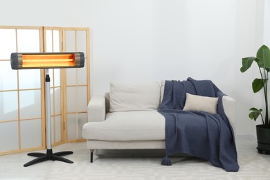 Photo of Electric infrared heater on floor in stylish room