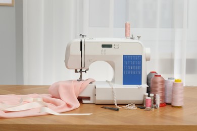 Photo of Sewing machine with fabric and craft accessories on wooden table indoors