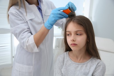 Photo of Doctor using nit comb on girl's hair in clinic. Anti lice treatment