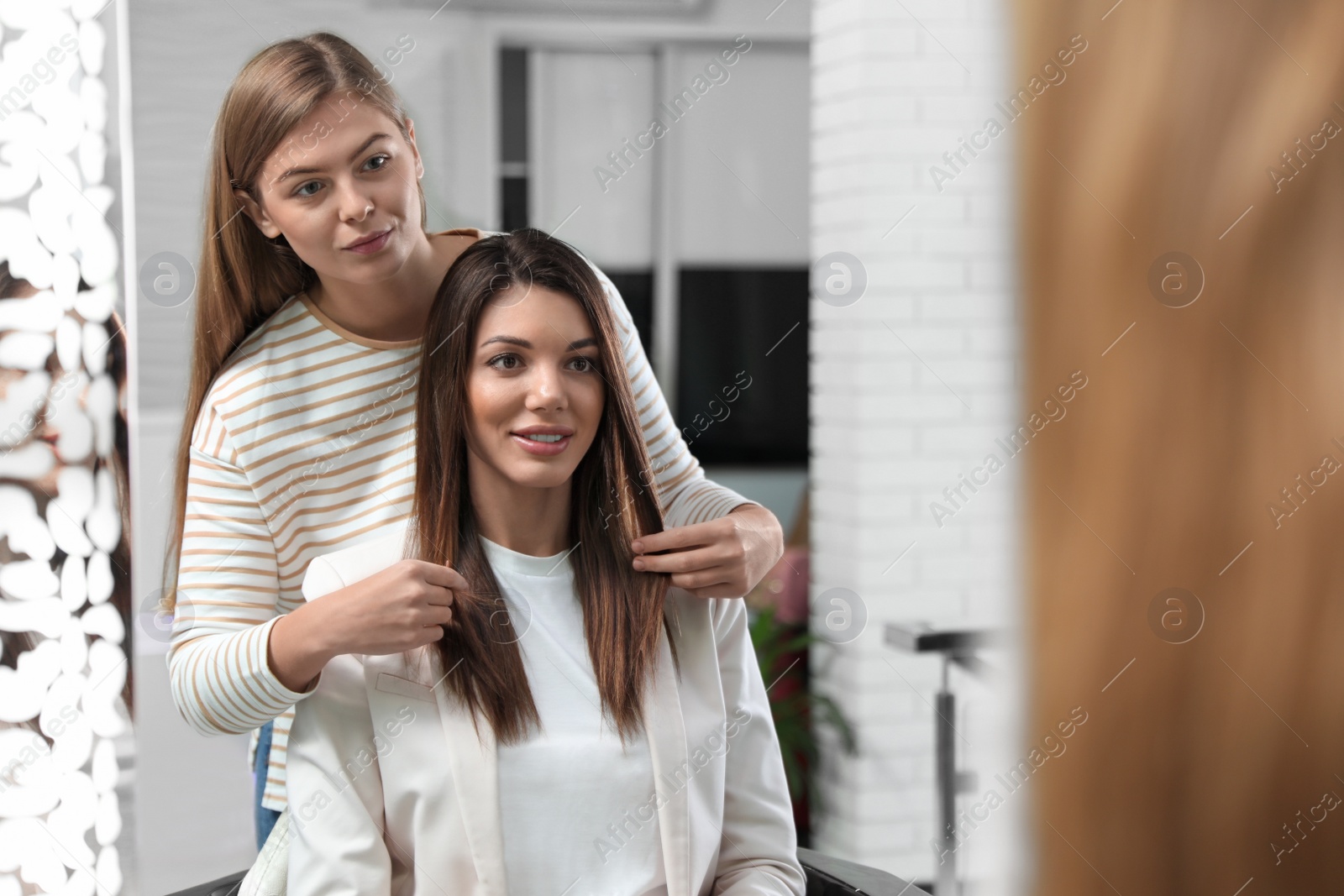 Photo of Professional hairdresser working with client in beauty salon