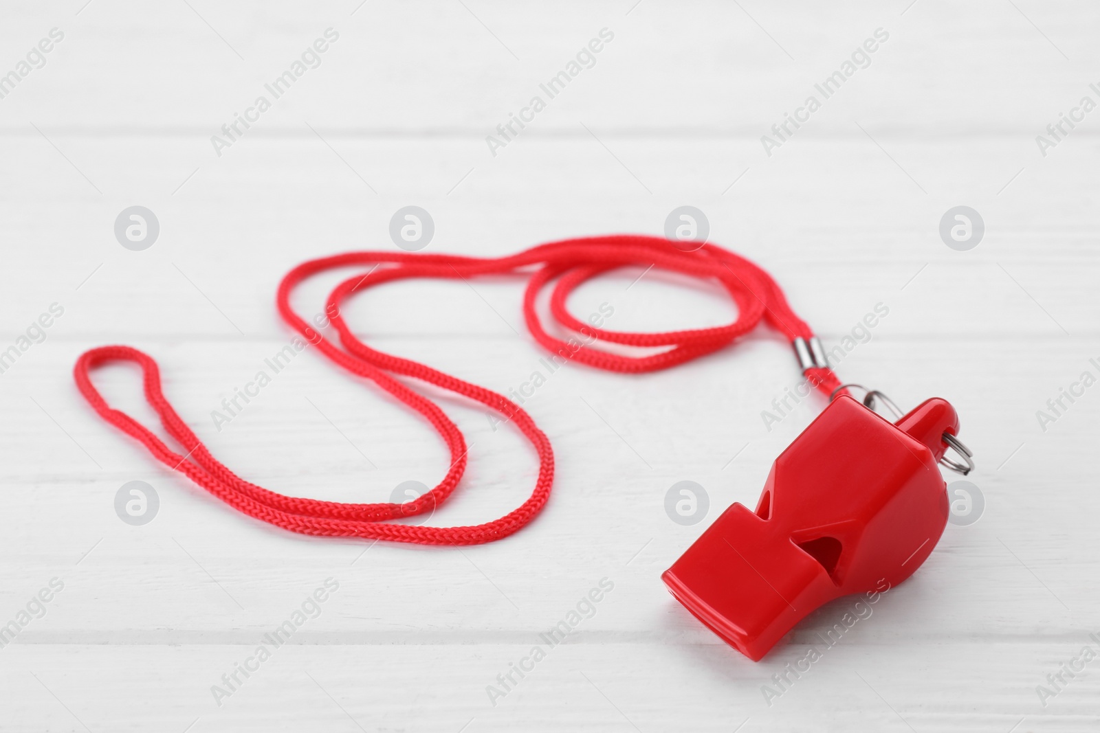 Photo of One red whistle with cord on white wooden table