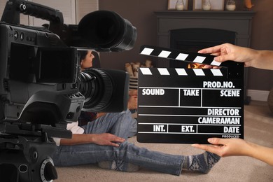Shooting movie. Second assistant camera holding clapperboard near video camera in front of couple (actors) in room with fireplace (film set)