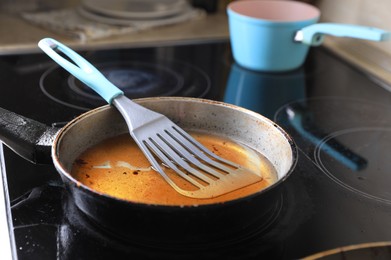 Frying pan with spatula and used cooking oil on stove