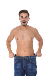 Fit man in oversized jeans on white background. Weight loss