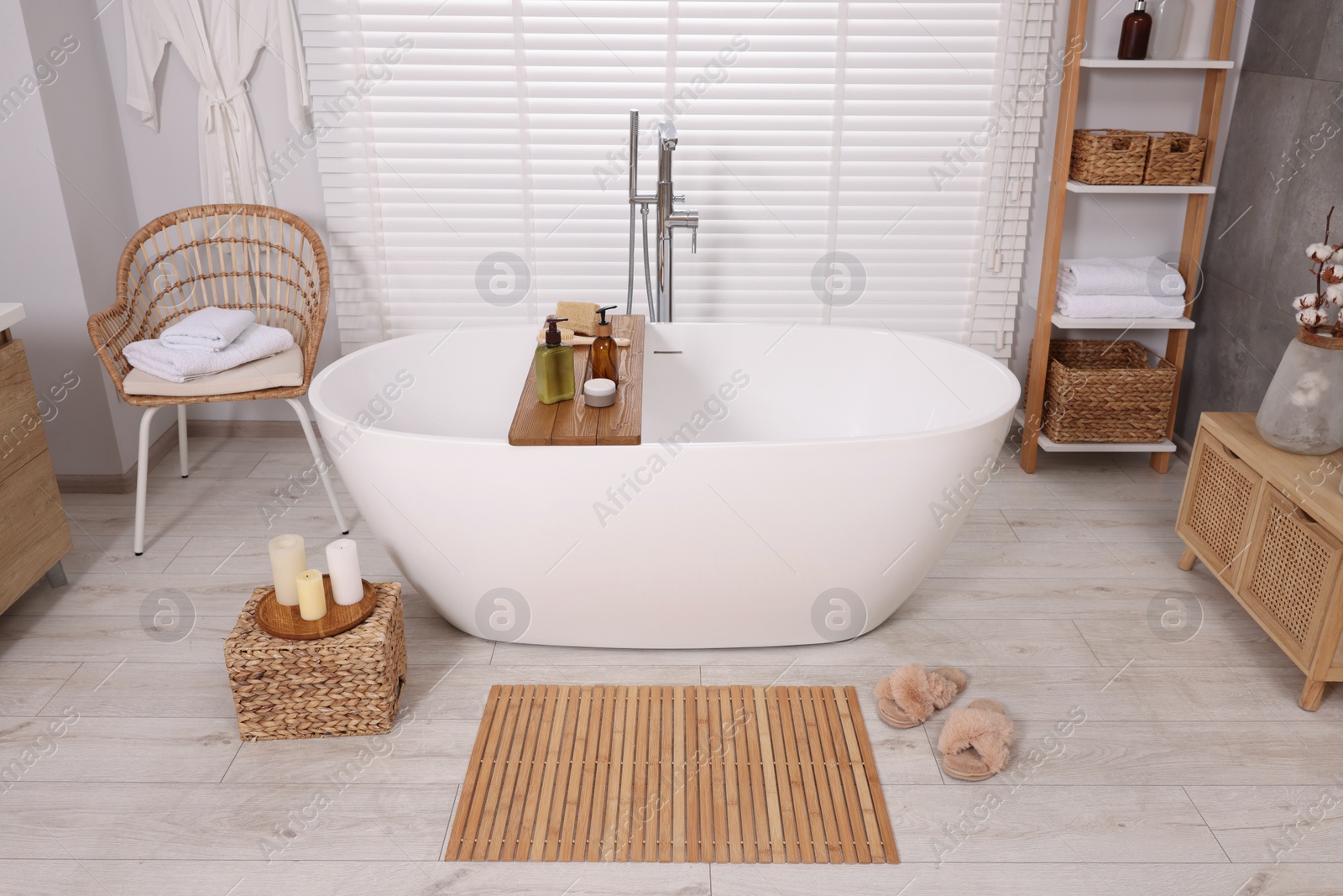 Photo of Stylish bathroom interior with bamboo bath mat and white tub