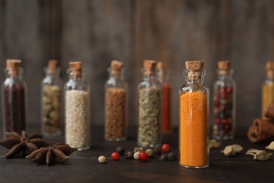 Bottles with different spices on table against blurred background