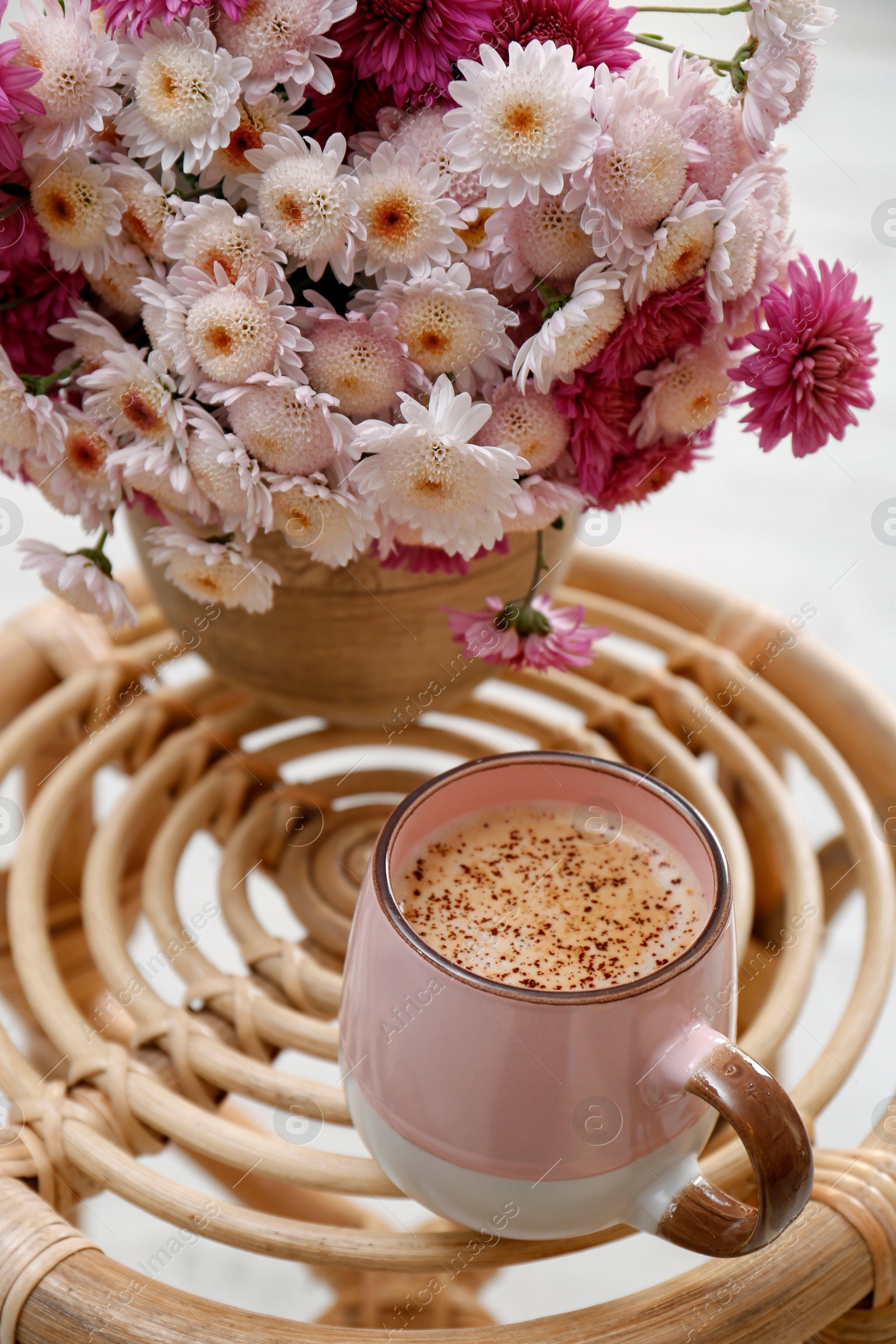 Photo of Cup of fresh coffee and beautiful bouquet on wooden stand. Good morning