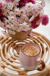 Photo of Cup of fresh coffee and beautiful bouquet on wooden stand. Good morning