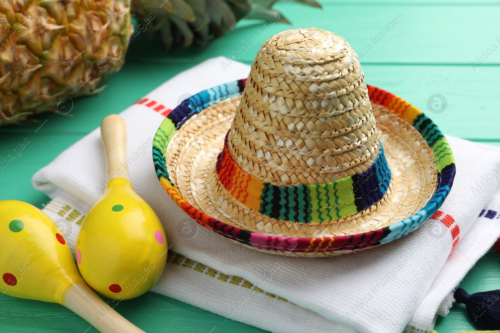 Photo of Mexican sombrero hat, maracas and poncho on turquoise wooden table