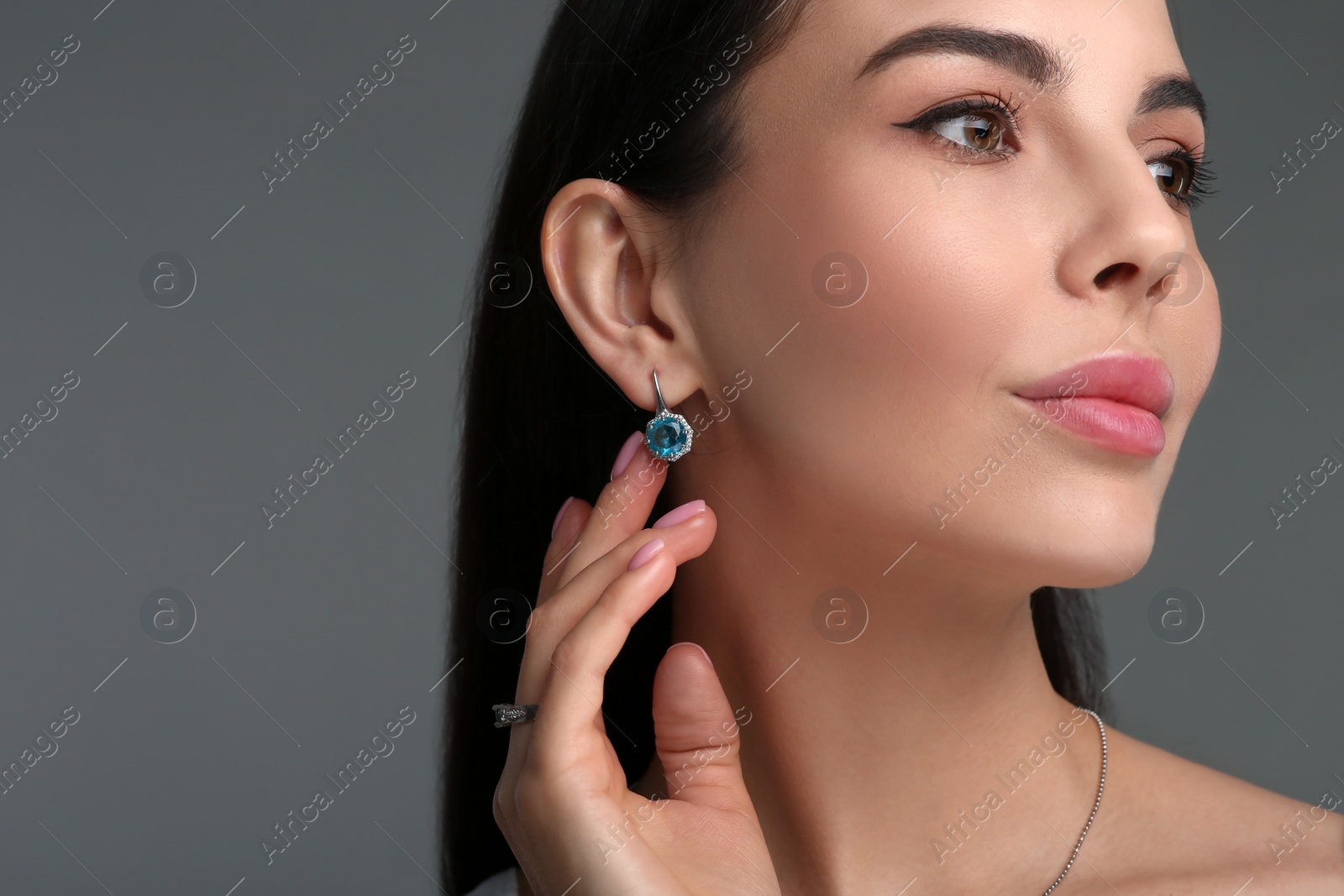 Photo of Beautiful young woman with elegant earrings on dark grey background, closeup