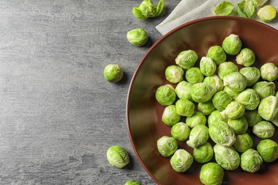 Photo of plate of fresh Brussels sprouts on grey background, top view with space for text