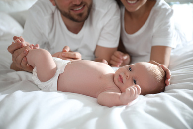 Photo of Happy couple with their newborn baby on bed, closeup