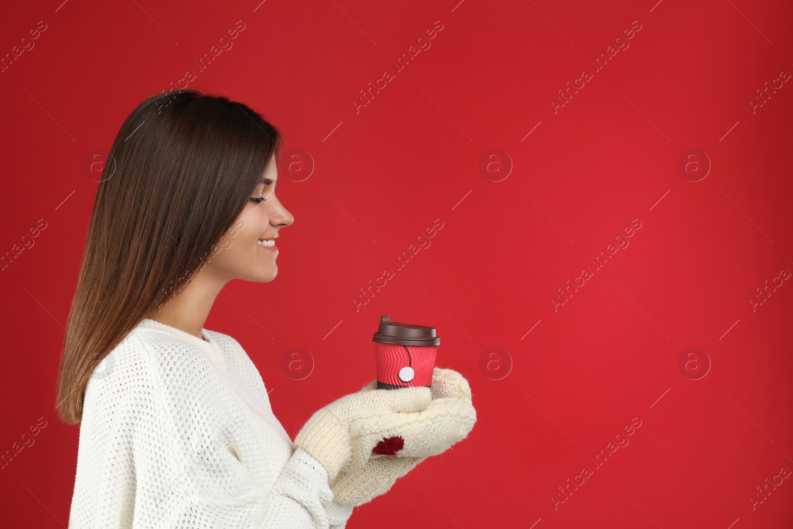 Photo of Happy beautiful woman with paper cup of mulled wine on red background. Space for text