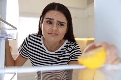 Upset woman near empty refrigerator in kitchen, view from inside