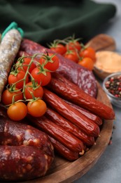 Photo of Different types of tasty sausages and ingredients on light grey table, closeup