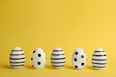 Photo of Line of traditional Easter eggs decorated with black paint on color background