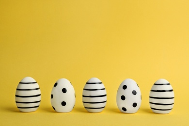 Line of traditional Easter eggs decorated with black paint on color background