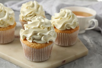 Photo of Tasty cupcakes with vanilla cream on grey table, closeup