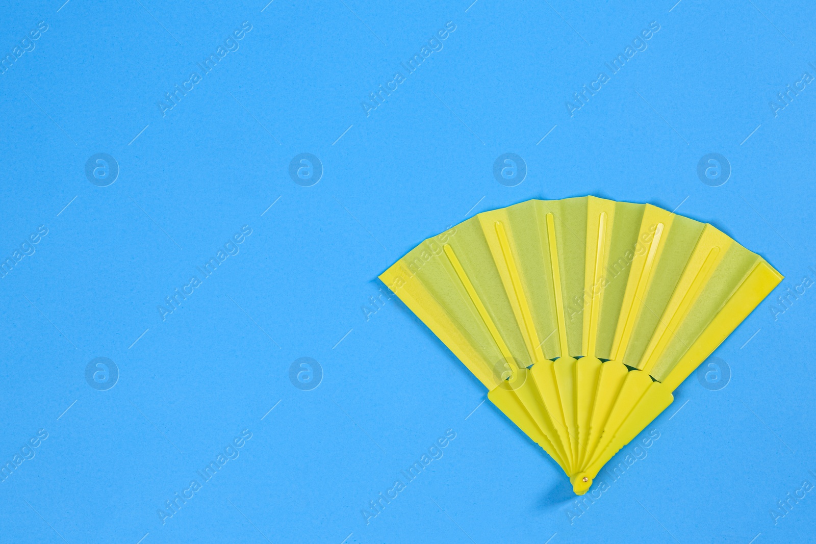 Photo of Yellow hand fan on light blue background, top view. Space for text