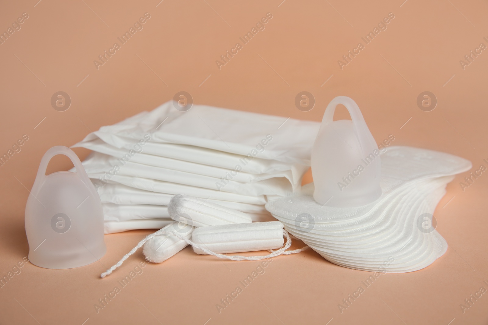 Photo of Menstrual pads and other period products on pale orange background