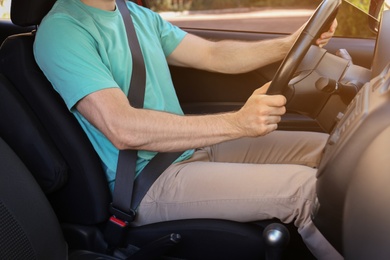 Man with fastened safety belt on driver's seat in car, closeup