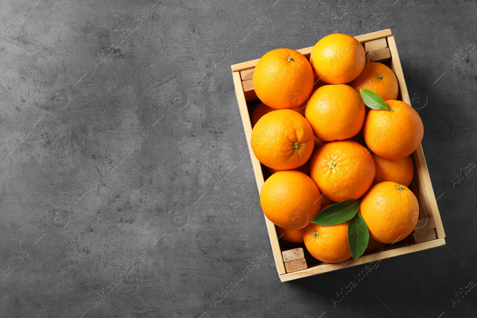 Photo of Wooden crate with ripe oranges on grey background, top view. Space for text