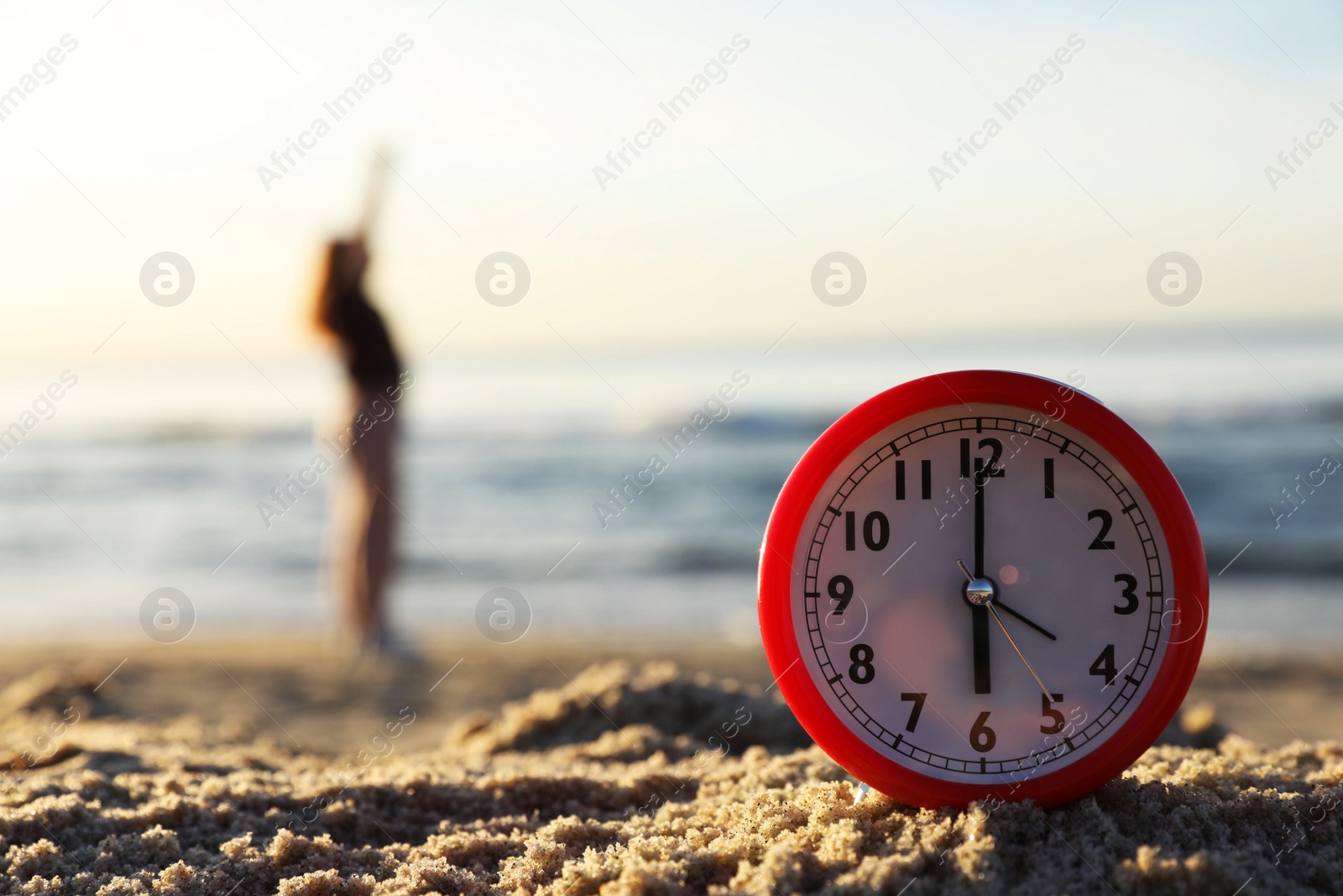 Photo of Woman doing morning exercises near river outdoors, focus on alarm clock