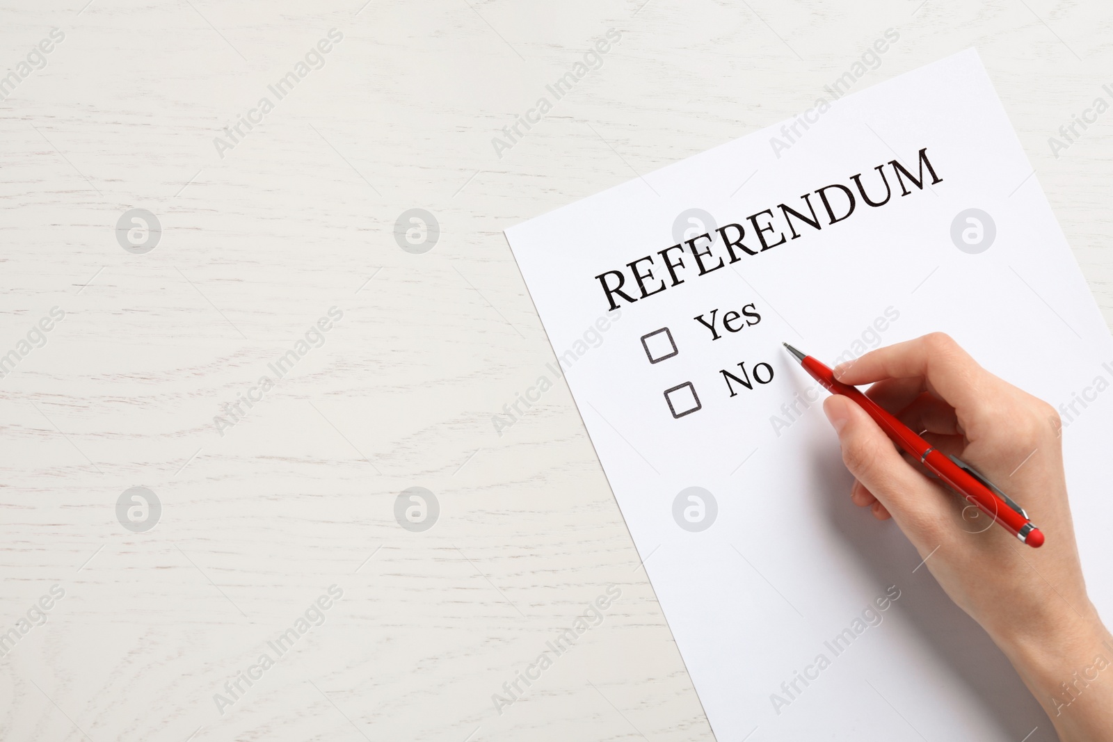 Photo of Woman with referendum ballot making decision at white wooden table, closeup. Space for text