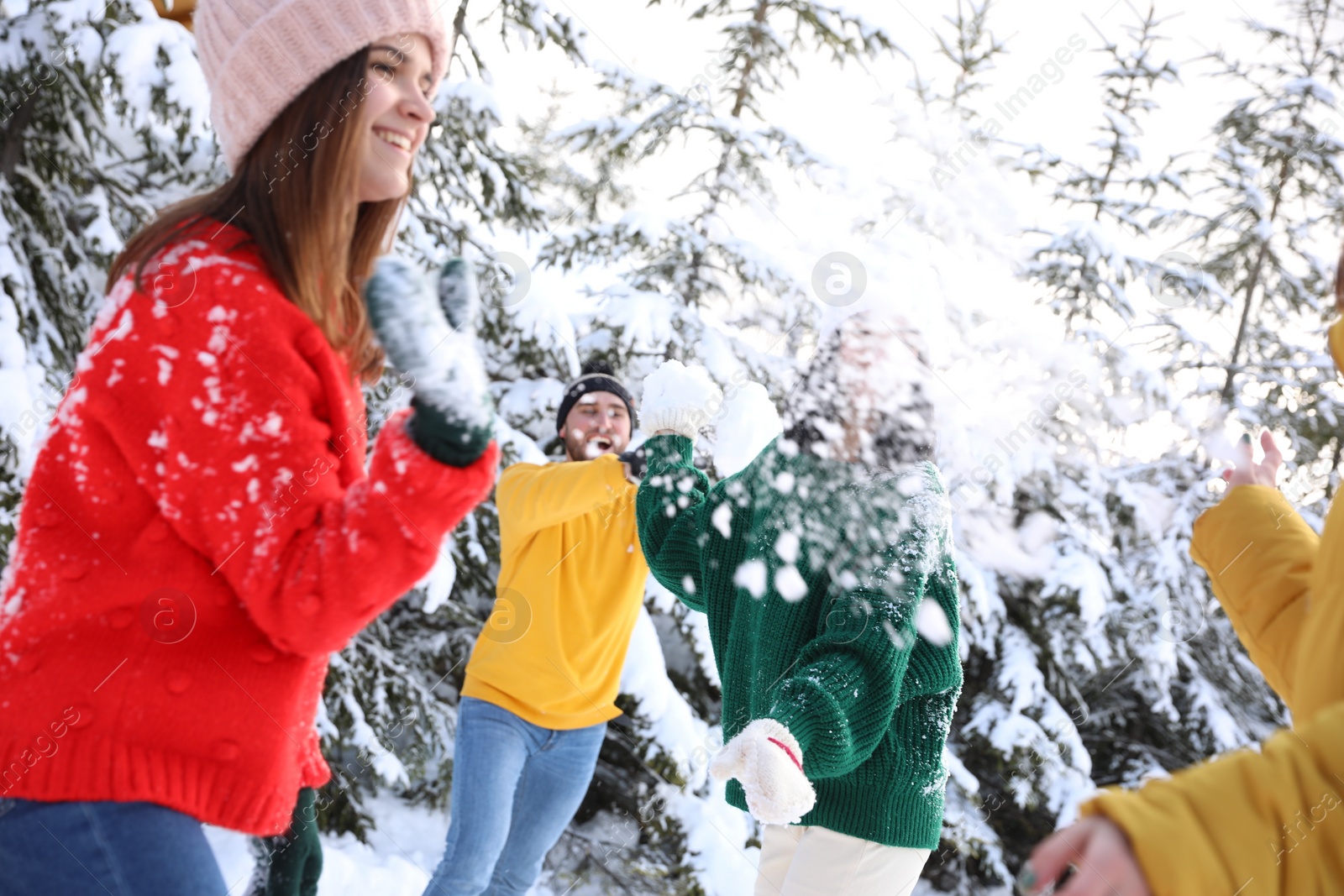 Photo of Happy friends playing snowballs outdoors. Winter vacation