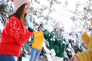 Happy friends playing snowballs outdoors. Winter vacation