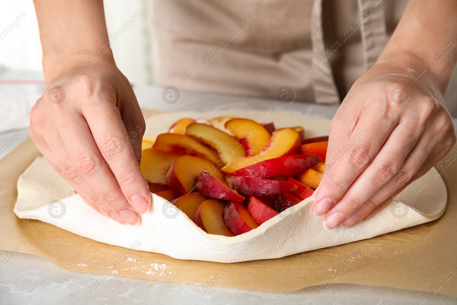 Photo of Woman making peach pie at kitchen table, closeup