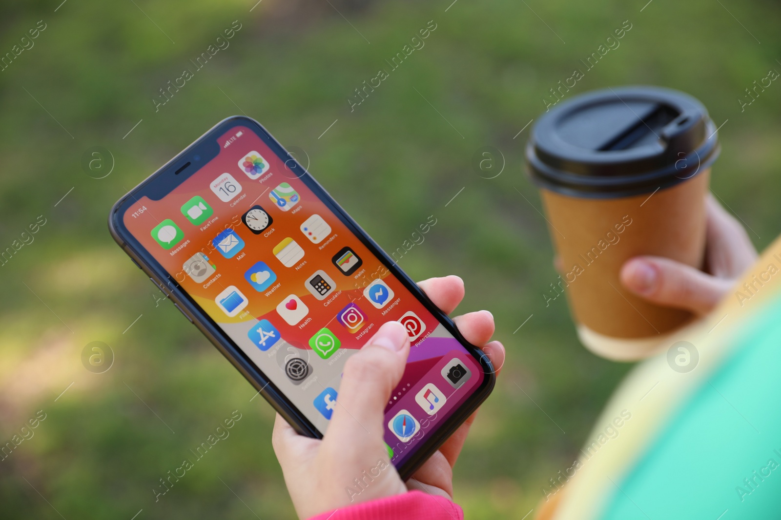 Photo of MYKOLAIV, UKRAINE - MARCH 16, 2020: Woman holding iPhone 11 with home screen outdoors, closeup