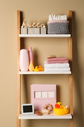 Photo of Towels, toys and baby accessories on wooden rack