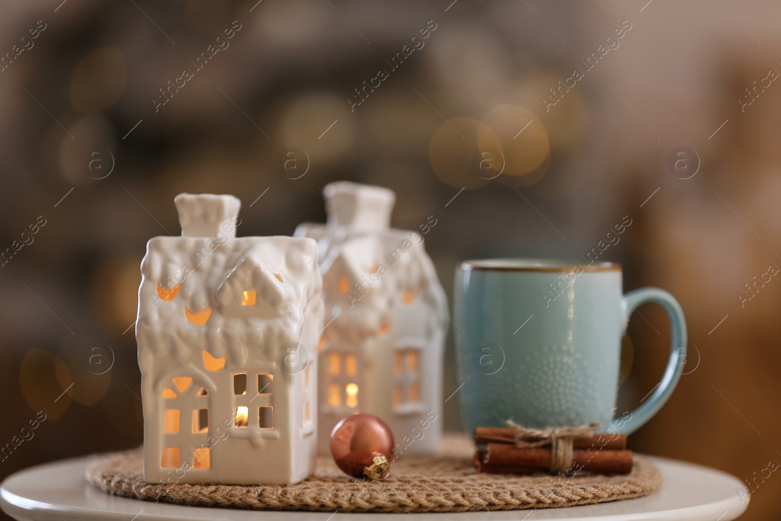 Photo of Composition with house shaped candle holder on white table against blurred background. Christmas decoration