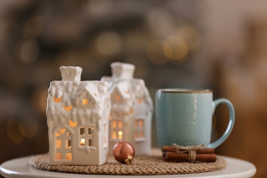 Photo of Composition with house shaped candle holder on white table against blurred background. Christmas decoration