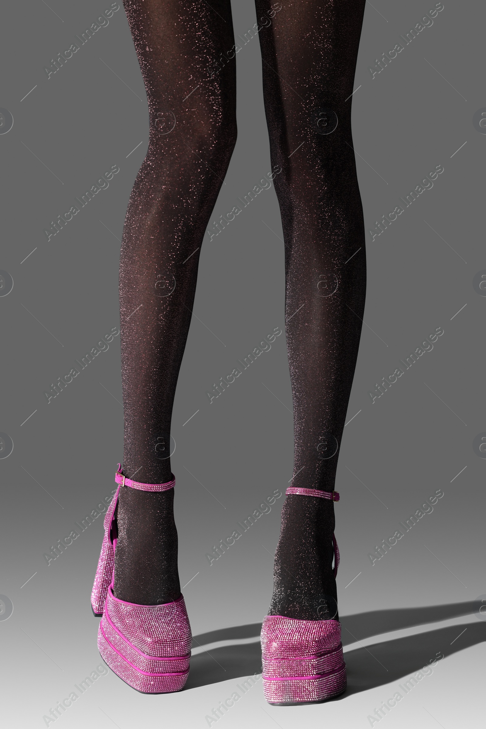Photo of Woman wearing pink high heeled shoes with platform and square toes on light grey background, closeup