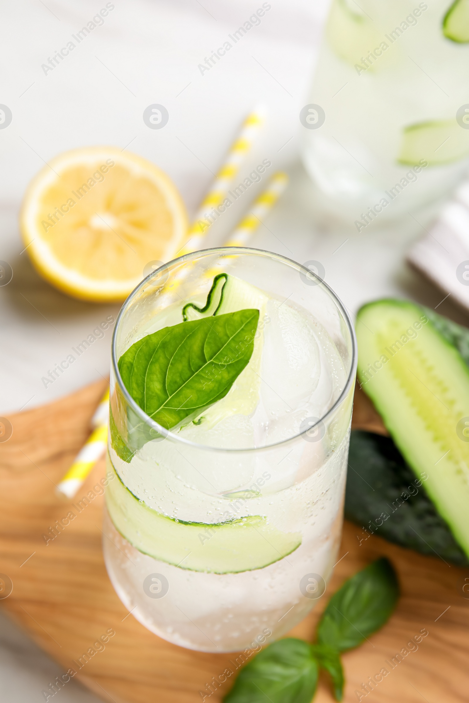 Photo of Tasty fresh cucumber water, sliced lemon and basil on white table, closeup