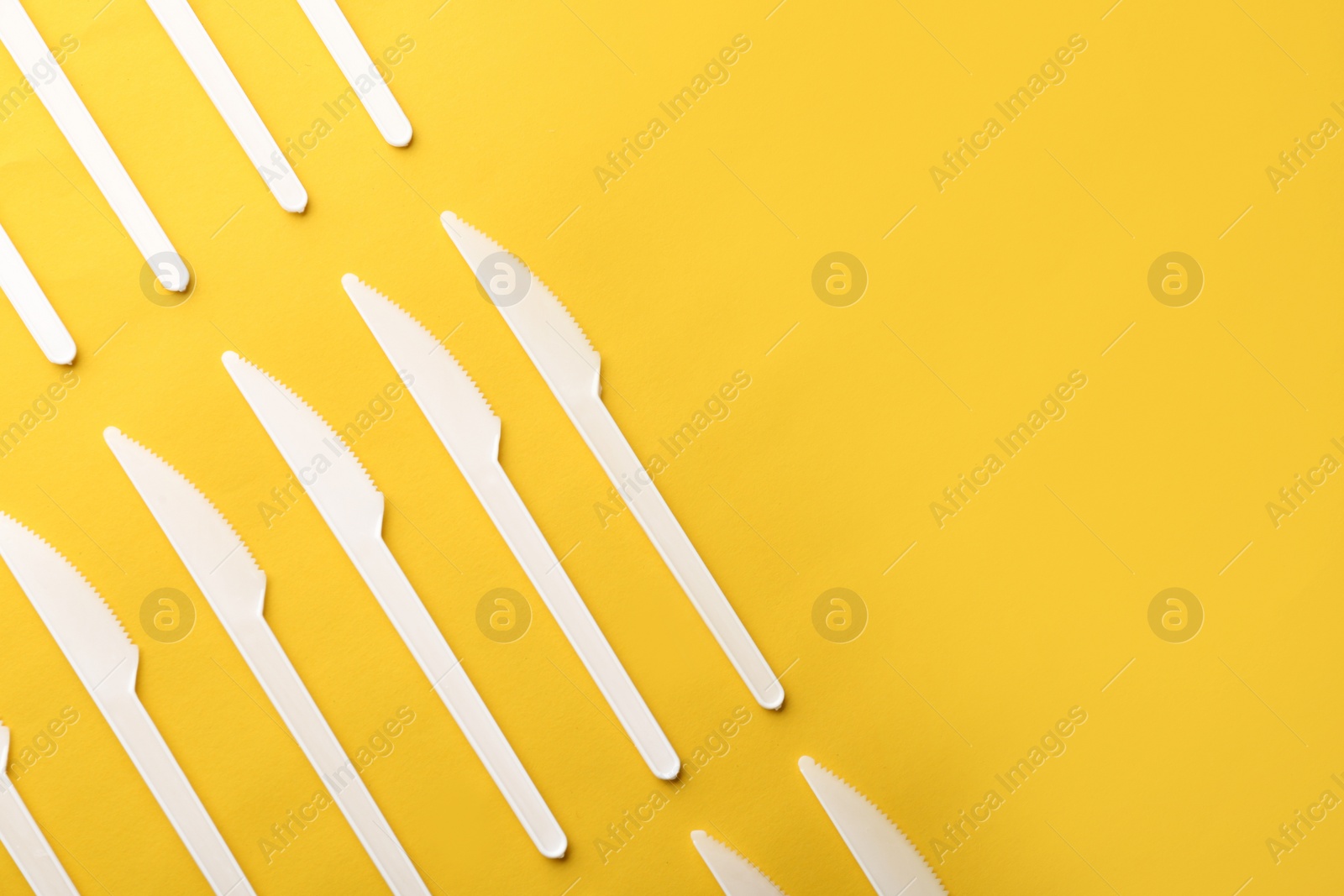 Photo of Plastic knives on color background, top view with space for text. Picnic table setting