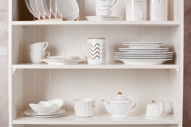 Photo of Stylish storage stand with different ceramic dishware at home