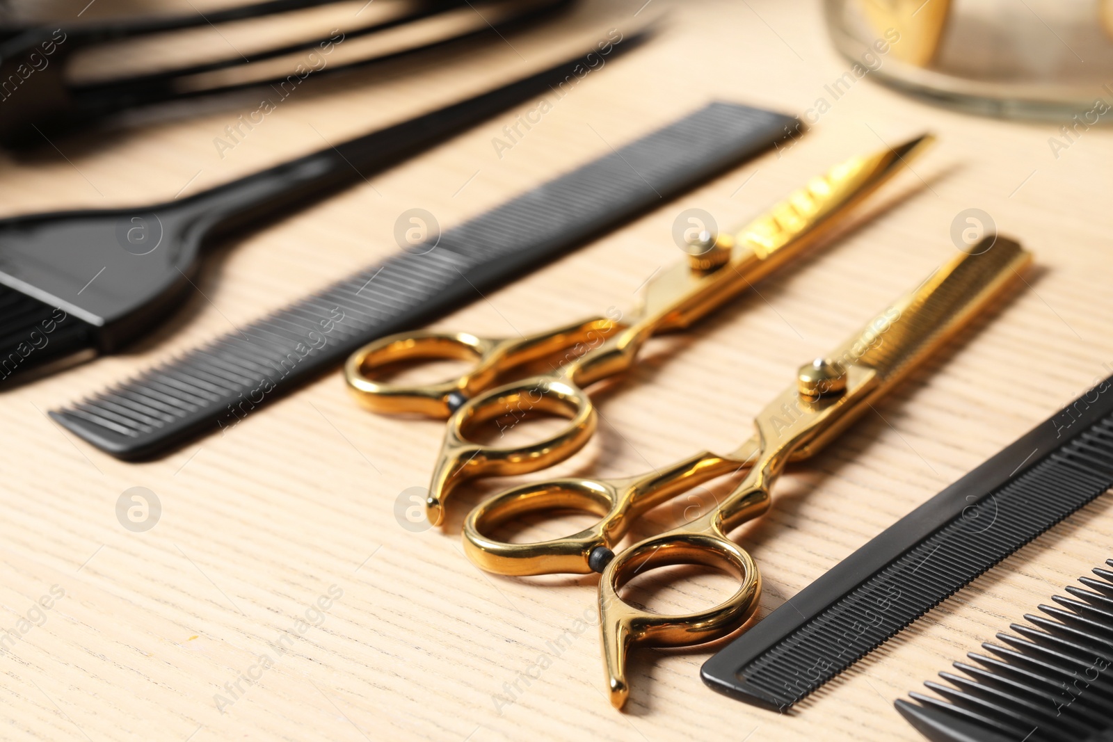 Photo of Hairdresser tools. Different scissors and combs on wooden table, closeup