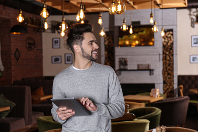 Young business owner with tablet in his cafe