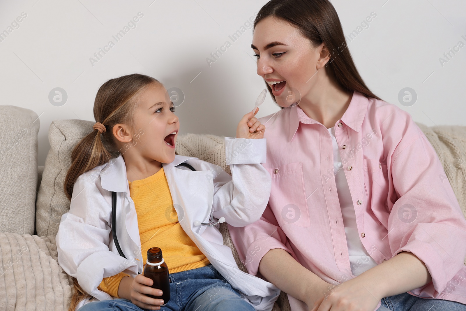 Photo of Little girl playing doctor with her mother at home