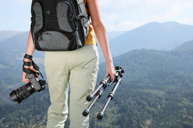 Photo of Professional photographer with modern camera and tripod in mountains, closeup