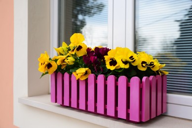 Photo of Beautiful bright violets in plant pot on windowsill outdoors