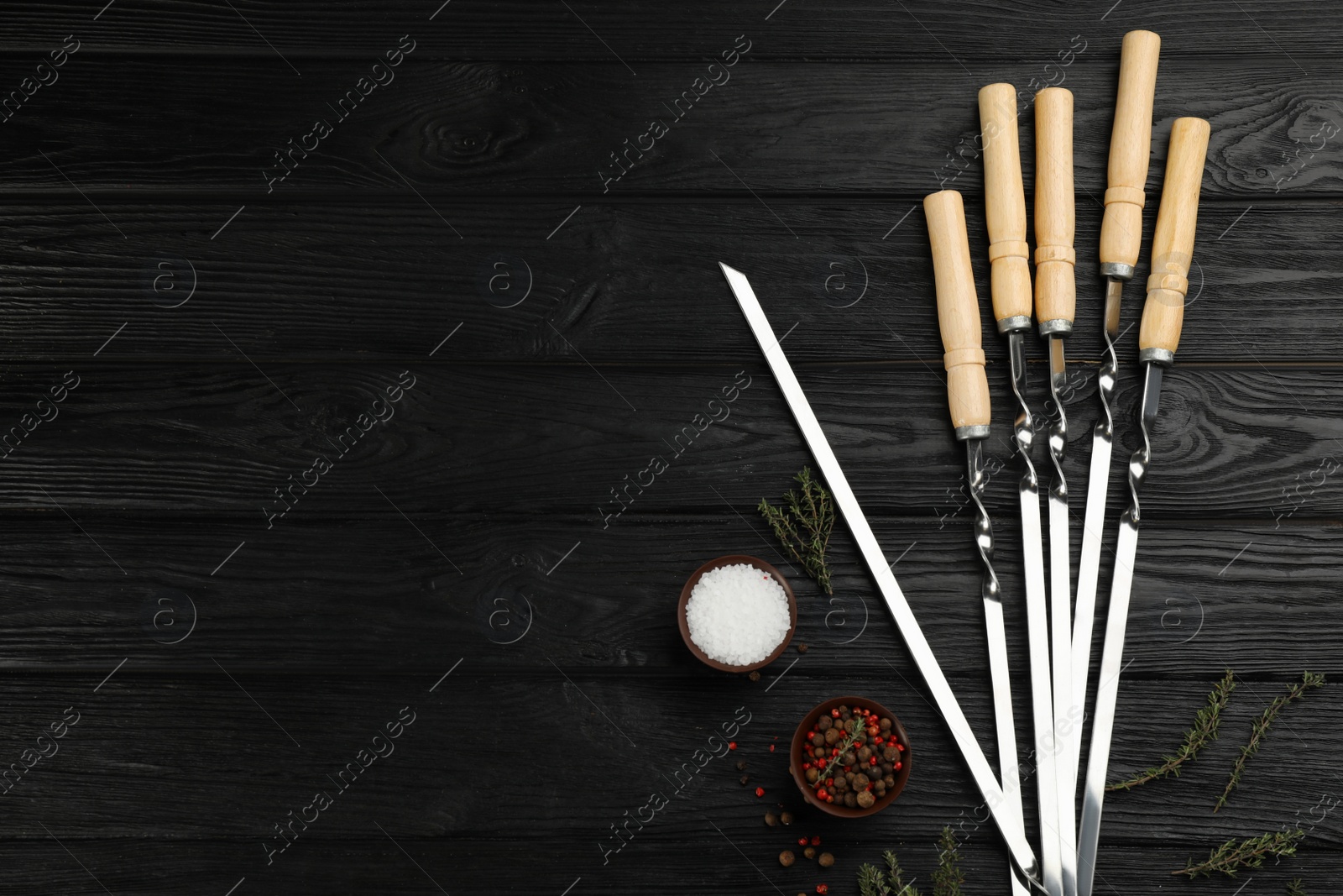 Photo of Flat lay composition with metal skewers on black wooden table. Space for text