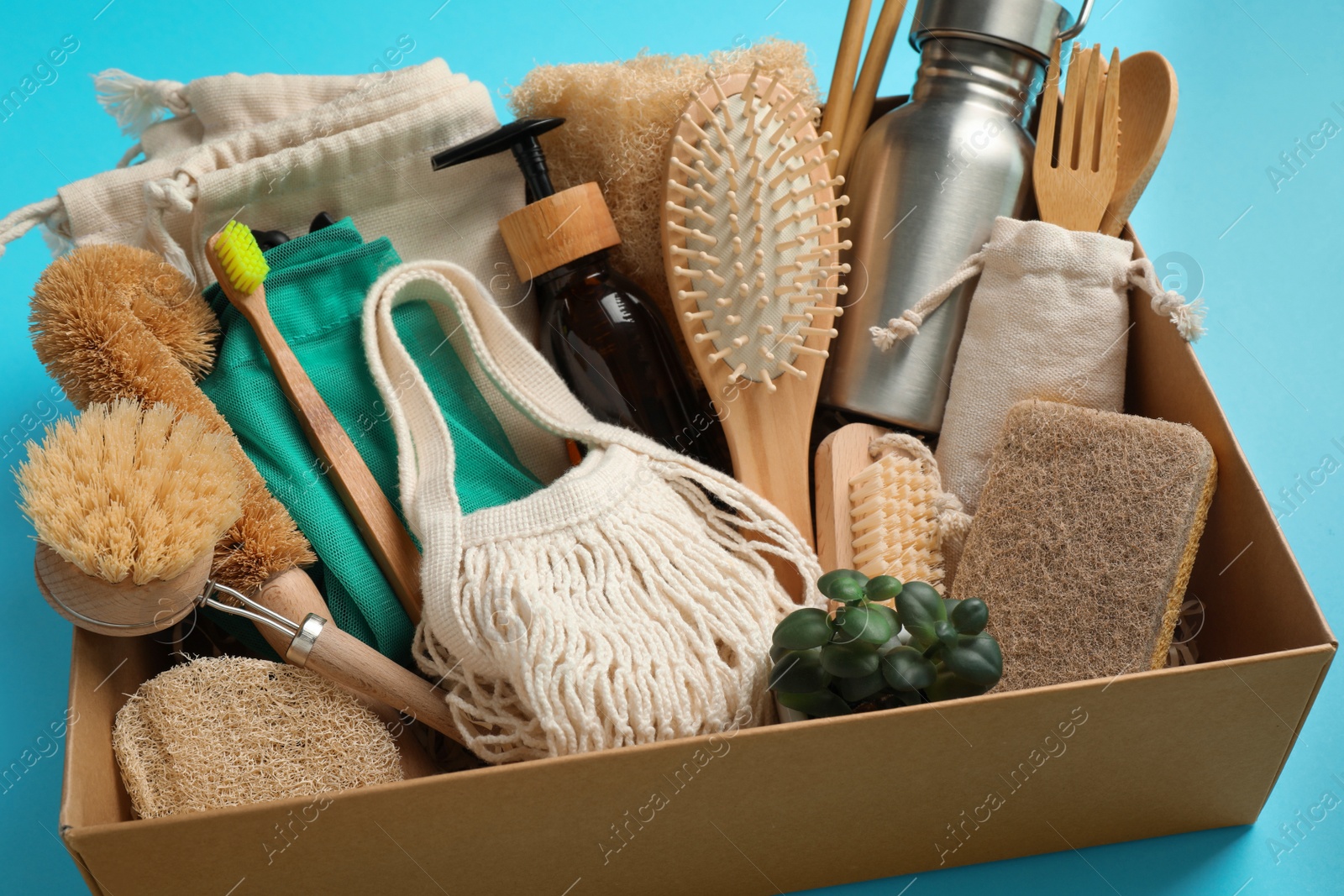 Photo of Cardboard box with eco friendly products on light blue background, closeup