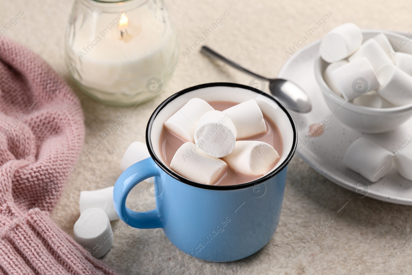 Photo of Cup of aromatic hot chocolate with marshmallows served on beige table, closeup