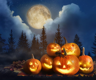 Image of Spooky Jack O Lantern pumpkins with creepy spider in misty forest under full moon on Halloween