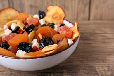 Photo of Bowl with different tasty dried fruits on wooden table, closeup. Space for text