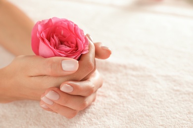 Photo of Closeup view of woman with smooth hands and flower on towel, space for text. Spa treatment